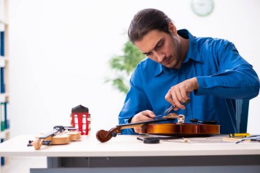 Kemanı tamir eden genç bir erkek tamirci
