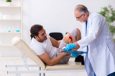 Yaralı adam ilk yardım konseptinde yaşlı doktoru ziyaret ediyor.