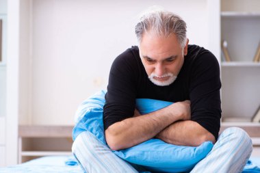 Mutsuz yaşlı adam yatak odasında.