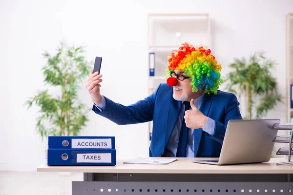 Oude zakenman clown werkt in het kantoor — Stockfoto