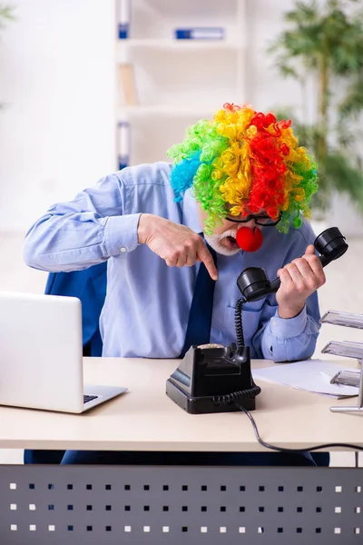 Oude zakenman clown werkt in het kantoor — Stockfoto