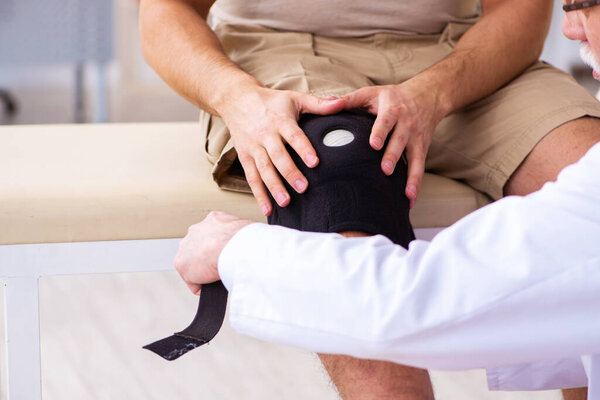 Experienced doctor traumatologist examining young male patient