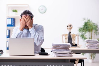 Genç erkek çalışan ve iskelet ofiste.