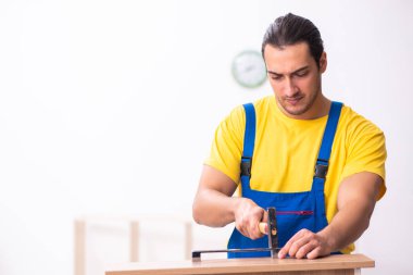 Genç erkek marangoz içeride çalışıyor.