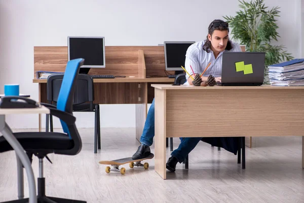 Ung manlig anställd med skateboard på kontoret — Stockfoto