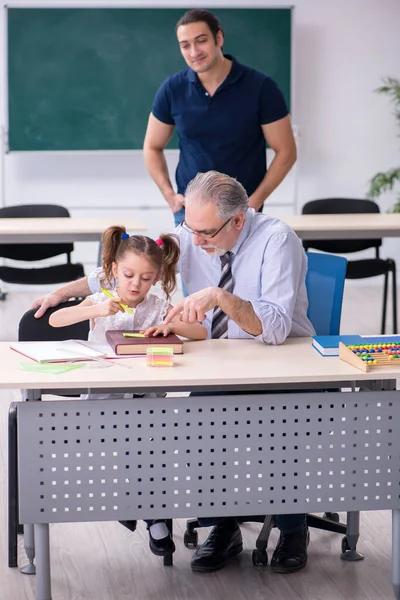 Jonge ouder, oude mannelijke leraar en klein meisje in de klas — Stockfoto