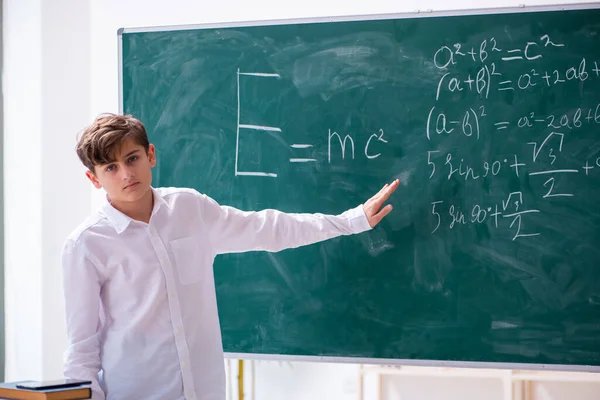 Schooljongen natuurkundige voor het groene bord — Stockfoto