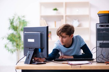 Çocuk atölyede bilgisayar tamir ediyor.