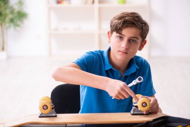 Çocuk evde kaykay tamir ediyor.