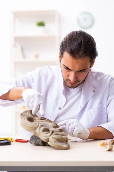 Jonge mannelijke archeoloog bestudeert het oude Afrikaanse steenmasker — Stockfoto