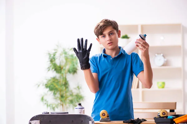 Jongen repareert skateboard thuis — Stockfoto