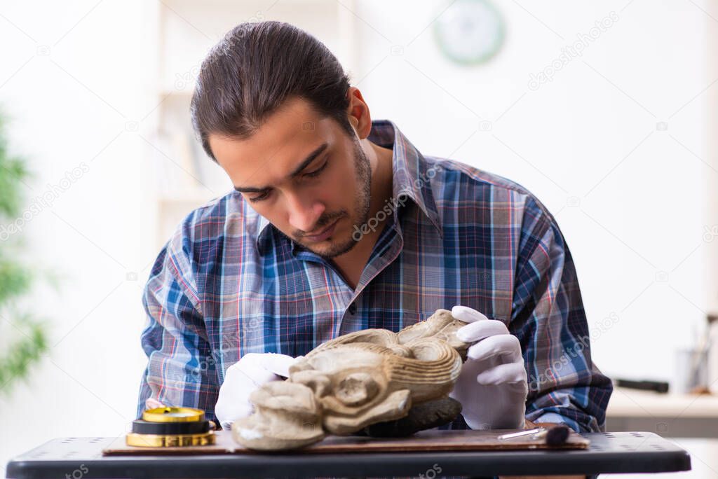 Young male archaeologist studying ancient african stonemask