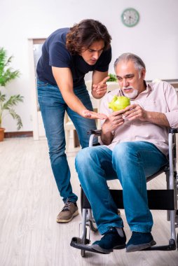 Tekerlekli sandalyedeki yaşlı adam ve genç kötü bakıcı.