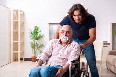 Tekerlekli sandalyedeki yaşlı adam ve genç kötü bakıcı.