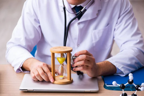 Young male doctor in time management concept