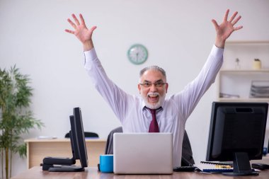 Eski erkek patron ofiste masaüstünde oturuyor.