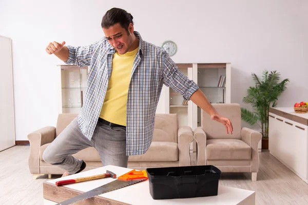 Genç erkek marangoz evde mobilya tamir ediyor. — Stok fotoğraf