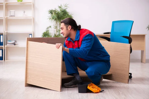 Joven contratista reparando muebles en la oficina — Foto de Stock