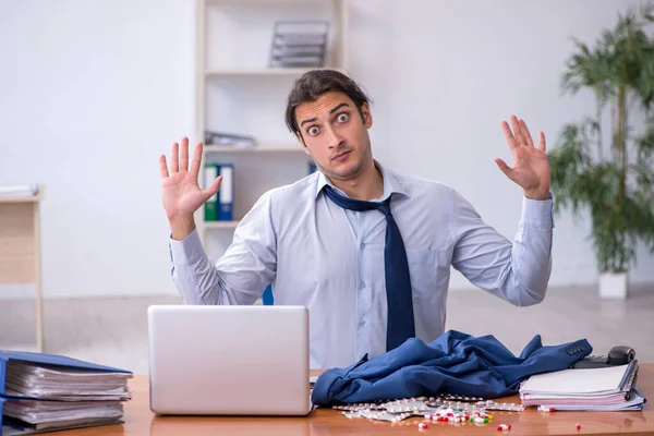 Ung manlig sjuk anställd som lider på arbetsplatsen — Stockfoto