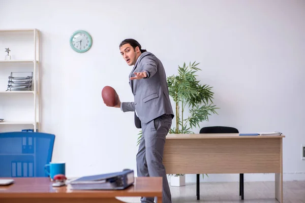 Young male employee with rugby ball in the office