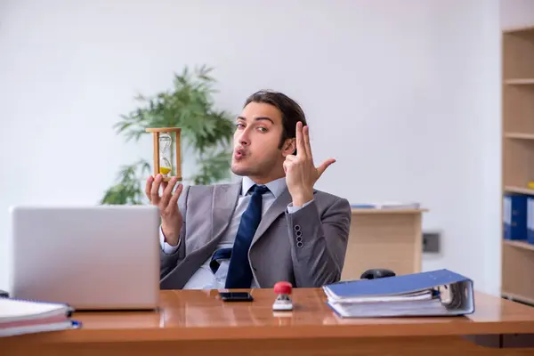 Joven empleado masculino en concepto de gestión del tiempo —  Fotos de Stock