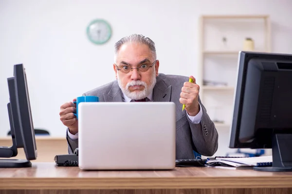 Vecchio capo maschio seduto sul desktop in ufficio — Foto Stock