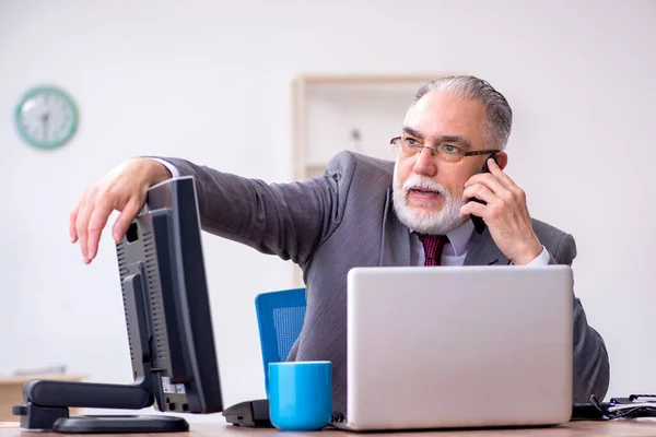 Old male boss sitting at desktop in the office — Stock Photo, Image