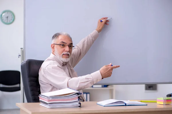 Oude mannelijke leraar zit in de klas — Stockfoto