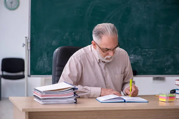 Starý muž učitel sedí ve třídě — Stock fotografie