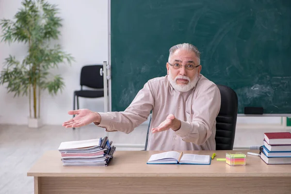 Vieux professeur assis dans la salle de classe — Photo