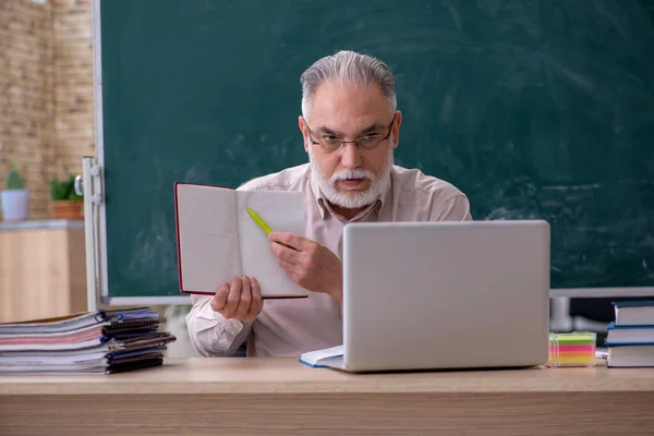 Oude mannelijke leraar zit in de klas — Stockfoto