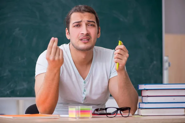 Jonge mannelijke leraar student zittend in de klas — Stockfoto