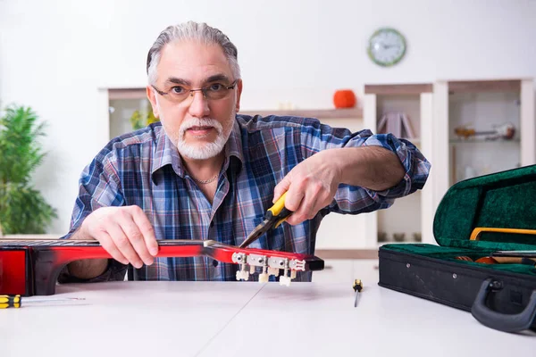 Senior manliga reparatör reparera musikinstrument hemma — Stockfoto