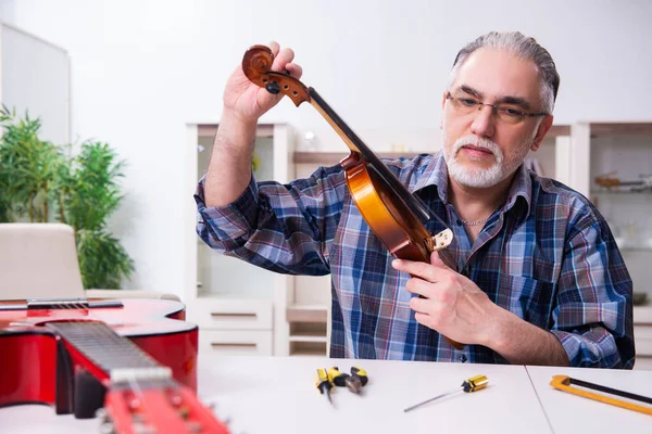 Idősebb férfi szerelő hangszereket javít otthon — Stock Fotó