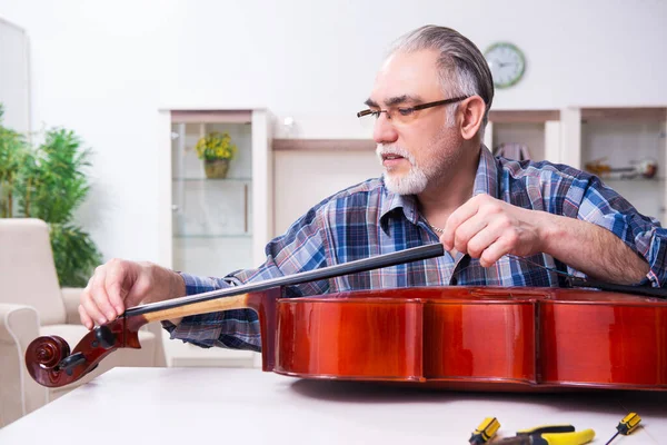 Réparateur masculin senior réparant des instruments de musique à la maison — Photo