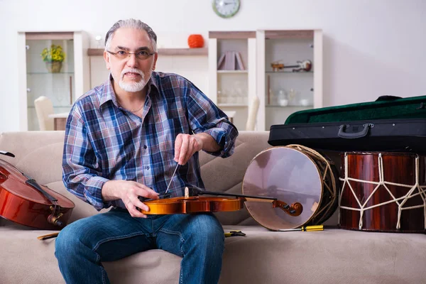 Hombre mayor reparador reparando instrumentos musicales en casa — Foto de Stock