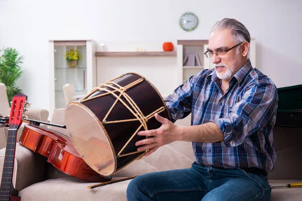 Senior mannelijke reparateur die thuis muziekinstrumenten repareert — Stockfoto