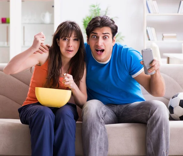 Joven hombre viendo fútbol con su esposa en casa — Foto de Stock