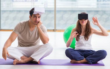 VR gözlüklü kadın ve erkek meditasyon yapıyor.
