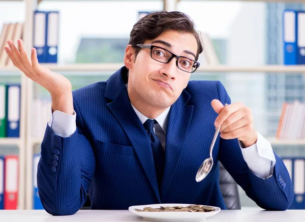 Забавный бизнесмен ест золотые монеты в офисе — стоковое фото