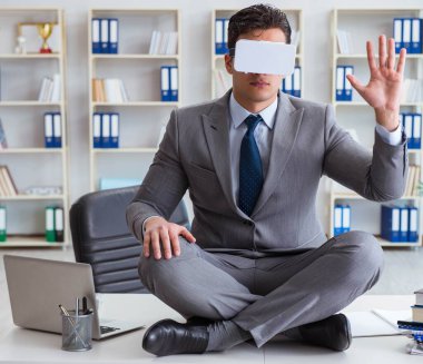 Sanal gerçeklikteki iş adamı VR gözlükleri masanın üstünde meditasyon yapıyor.