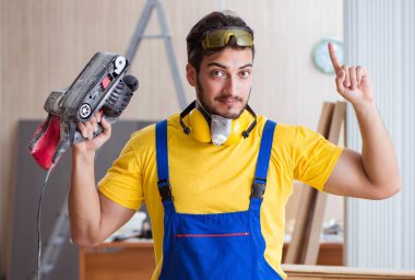 Elektrikli aletlerle çalışan genç marangoz.