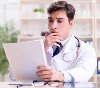 Genç doktor ofiste oturuyor.