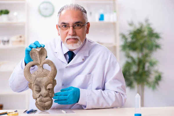 Archéologue principal étudiant l'ancien masque de pierre africaine — Photo