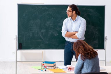 Genç bayan öğrenci ve erkek öğretmen sınıfta.