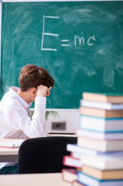 Yeşil panonun önündeki fizikçi çocuk.