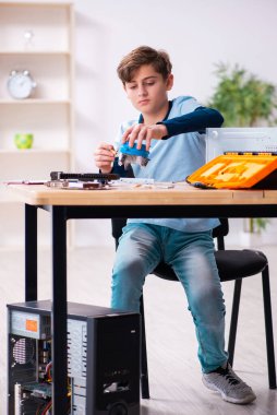 Çocuk atölyede bilgisayar tamir ediyor.