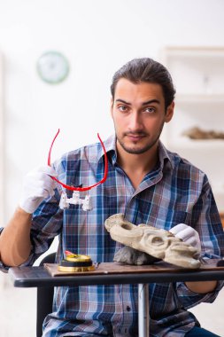 Genç erkek arkeolog eski Afrika taş maskesi üzerinde çalışıyor.