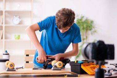 Çocuk kaykayı tamir ediyor ve blogu için video kaydediyor.