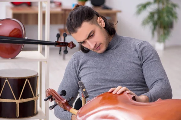 Молодой ремонтник чинит виолончель — стоковое фото
